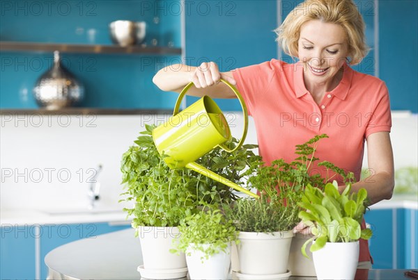 Caucasian woman watering plants in kitchen