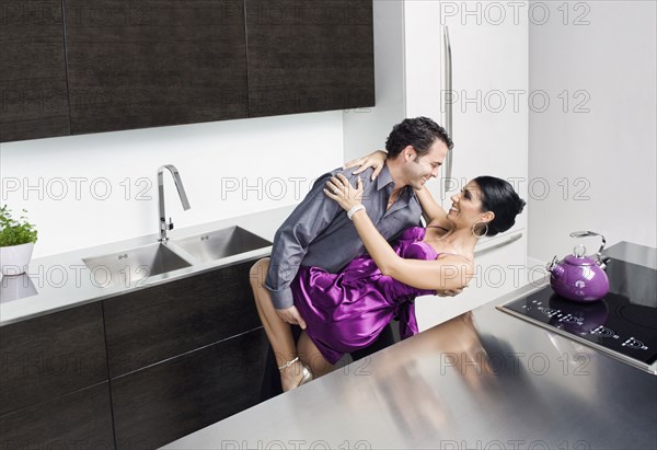 Caucasian couple hugging in kitchen