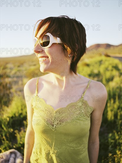 Smiling Caucasian woman wearing sunglasses in field