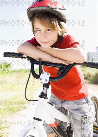 Caucasian boy leaning on bicycle handlebar