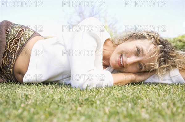 Portrait of smiling Caucasian woman laying in grass