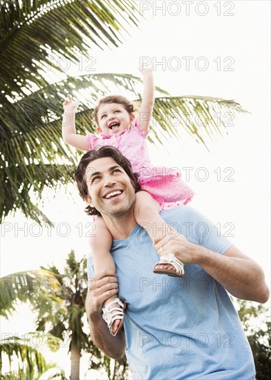 Caucasian father carrying baby daughter on shoulders