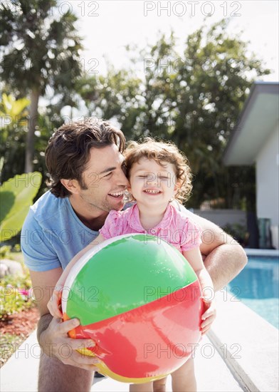 Caucasian father and baby daughter playing with beach ball
