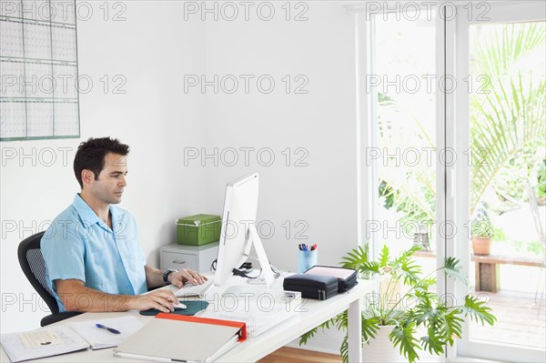 Mixed Race man using computer in home office