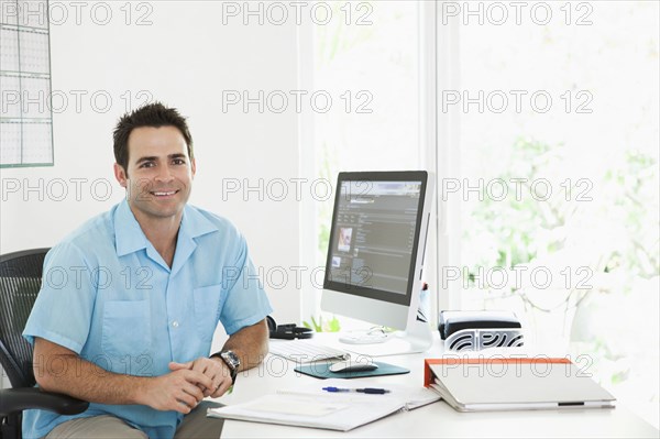 Portrait of Mixed Race man sitting at desk in home office