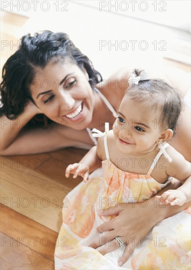 Mixed Race mother laying on floor holding baby daughter