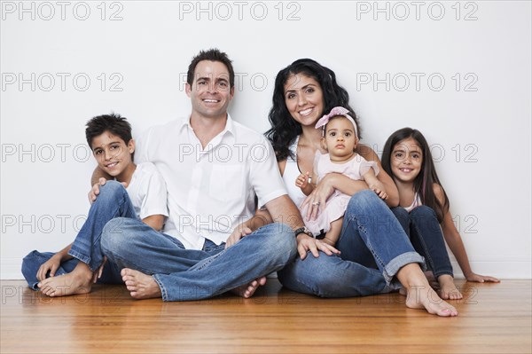 Portrait of smiling Mixed Race family sitting on floor