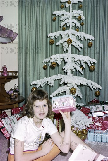 Caucasian girl sitting on floor showing Christmas gift