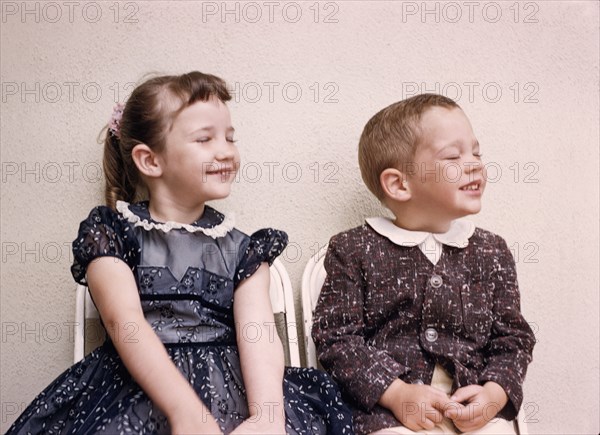 Caucasian brother and sister smiling with eyes closed