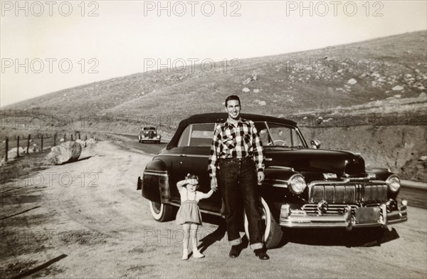 Portrait of Caucasian father and daughter posing near vintage car