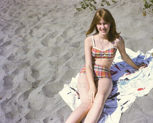 Portrait of smiling Caucasian teenage girl sitting on blanket at beach