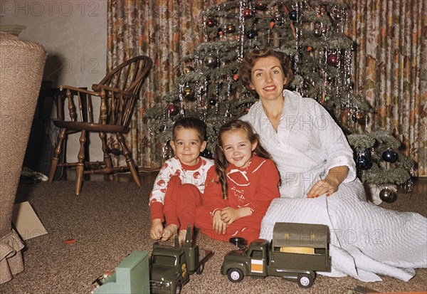 Caucasian mother posing with son and daughter near Christmas tree