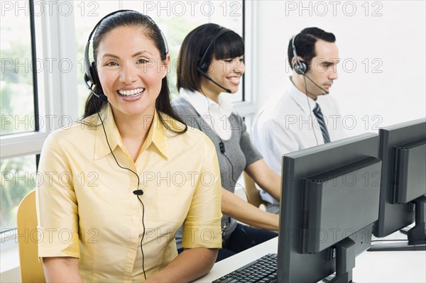 Customer service representatives wearing headsets using computers