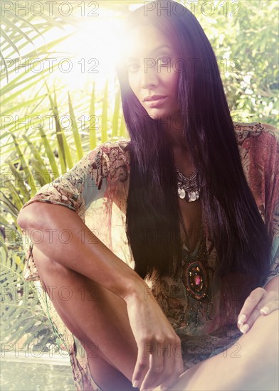 Exotic Hispanic woman sitting near foliage