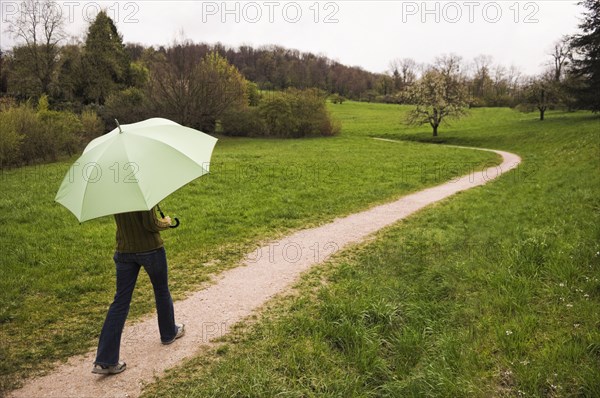 Mixed Race woman carrying umbrella on path