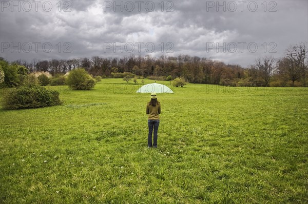 Mixed Race holding umbrella in field