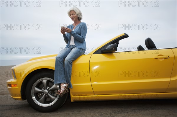 Caucasian woman sitting on convertible at beach