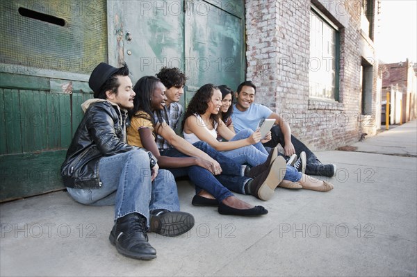 Friends hanging out together in urban area using digital tablet