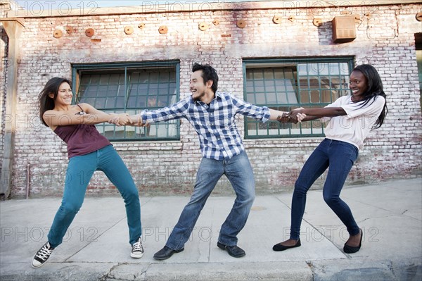 Women pulling on male friend's arms