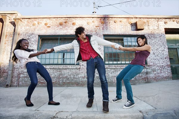 Women pulling on male friend's arms