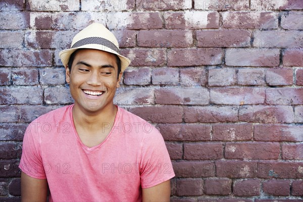 Smiling Asian man near brick wall