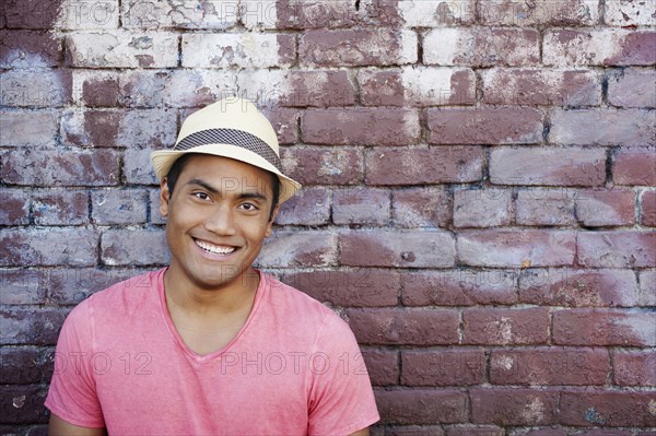 Smiling Asian man near brick wall