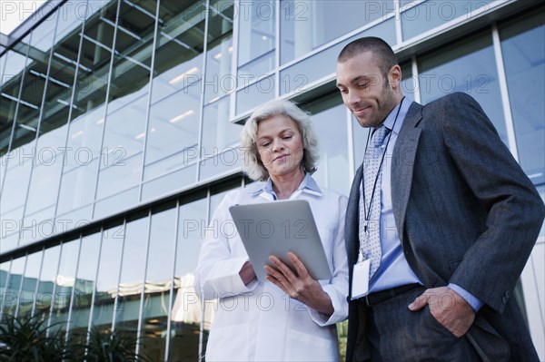 Doctor and businessman using digital tablet outdoors