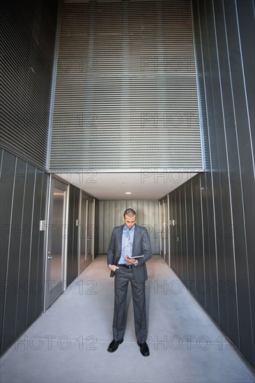 Businessman using digital tablet in corridor