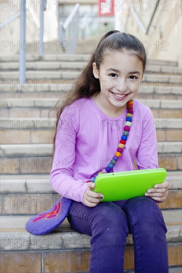 Mixed race girl using digital tablet on staircase