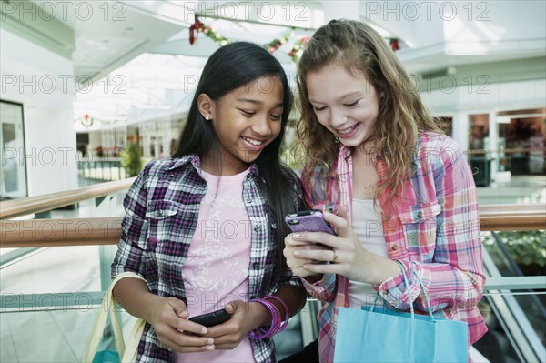 Friends looking at cell phone in shopping mall