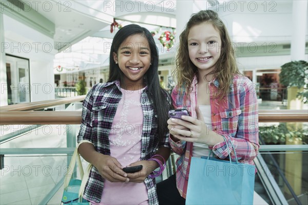 Friends holding cell phones in shopping mall