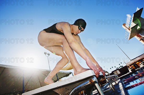 Competitive swimmer crouching on starting block
