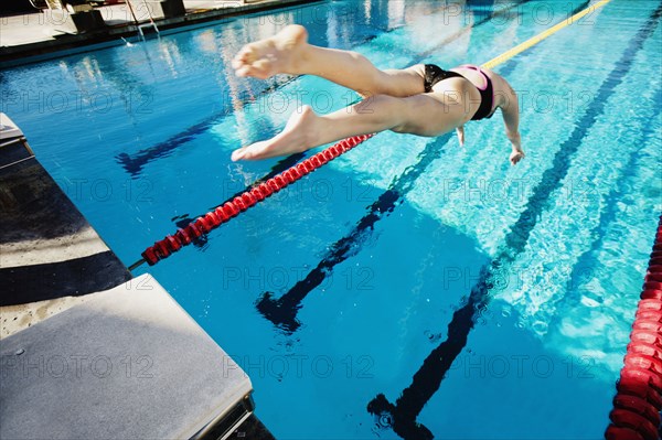 Competitive swimmer diving into swimming pool