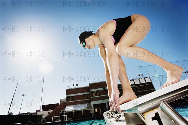 Competitive swimmer crouching on starting block