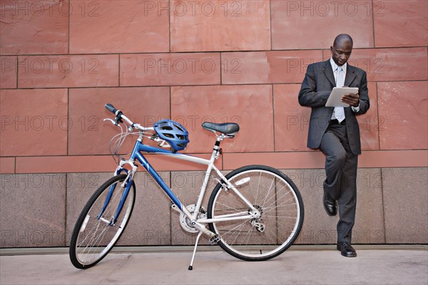 Businessman using digital tablet near bicycle