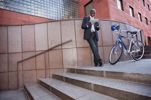 Businessman standing near bicycle using digital tablet