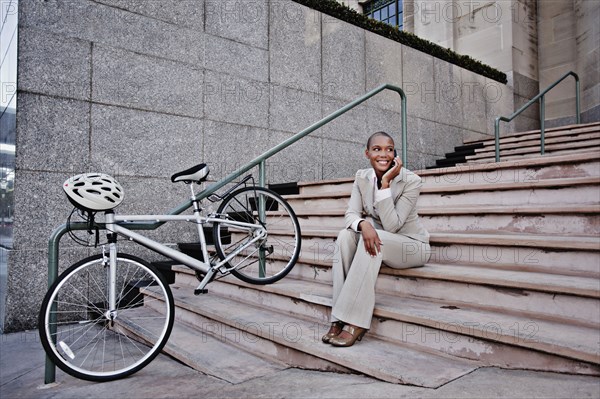 Businesswoman sitting in stairs talking on cell phone