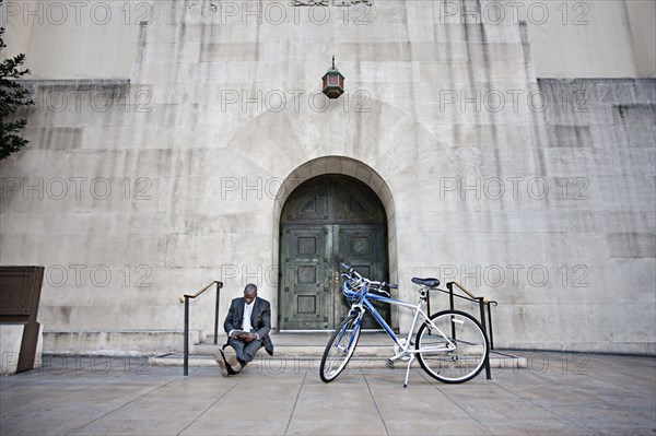 Businessman sitting on steps near bicycle