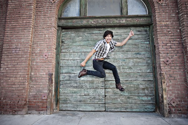 Mixed race man jumping on urban sidewalk