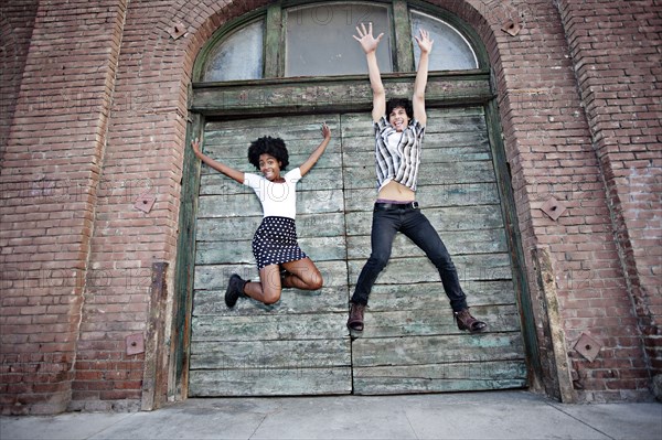 Friends jumping on urban sidewalk