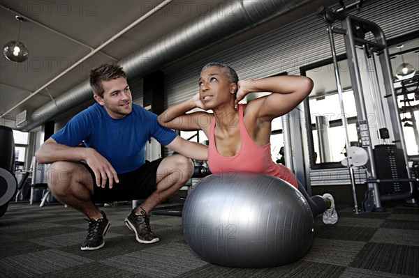 Personal trainer helping woman in health club