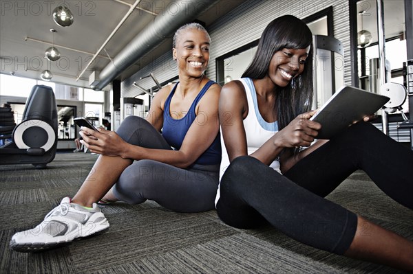 Women using digital tablet in health club