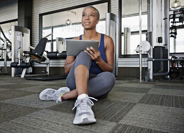 African American woman using digital tablet in health club