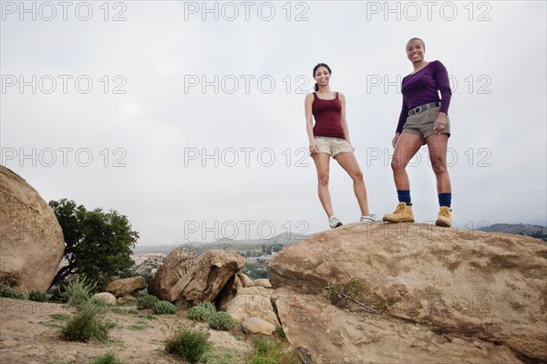 Mother and daughter standing on top of rock