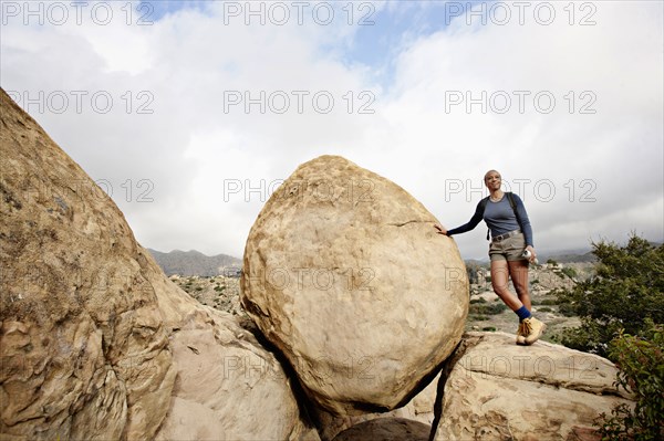 Black woman leaning against rock