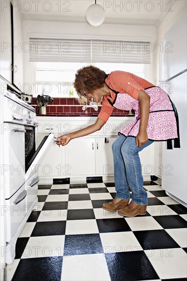 African American woman looking in oven