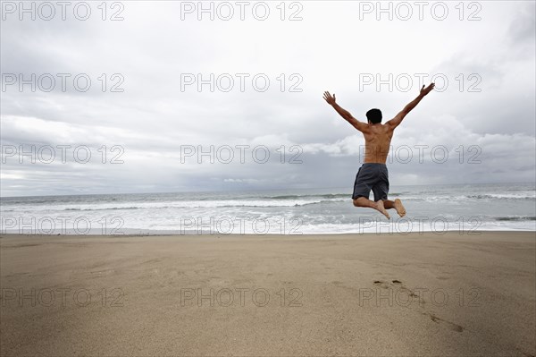 Young man jumping for joy on beach