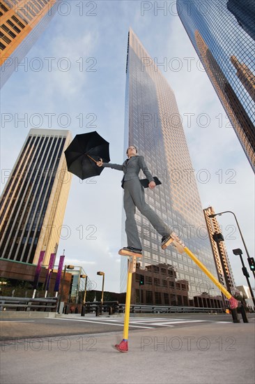 Caucasian businesswoman walking on stilts in urban environment