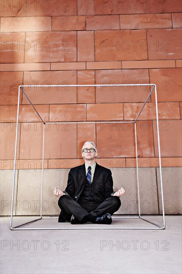 Caucasian businessman practicing yoga on sidewalk