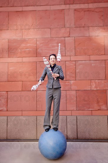 Caucasian businesswoman standing on ball juggling